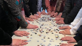 People placed hands on the table with puzzle pieces