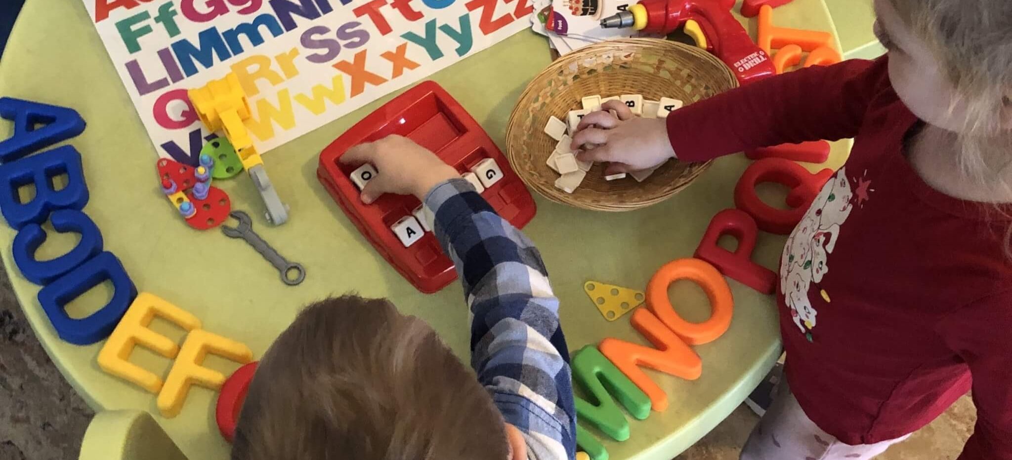 2 kids playing with letters and other toys on the table
